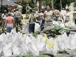 Residents, volunteers and National Guard troops work to build a sand bag levee around the town of in Hamburg, Ill. Friday, June 20.
