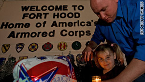 Army Spc. Ryan Hill and daughter, Emma, 3, light a candle Saturday near the main gate of Fort Hood in Texas.
