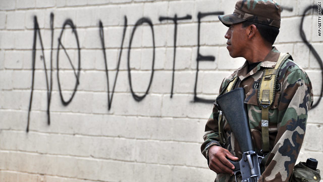 A Honduran soldier stands guard Friday in Tegucigalpa near graffiti urging a boycott of this weekend's election.