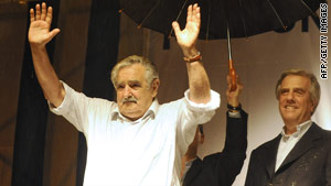 Jose Mujica waves to supporters Sunday as outgoing Uruguyan President Tabare Vazquez, right, looks on.