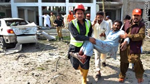 Rescuers carry a man hurt in Friday's blast in Peshawar.