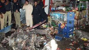 Pakistani police stand beside the wreckage from a suicide car bomb in Peshawar on Tuesday.