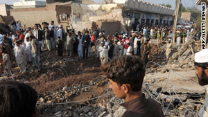 Local residents gather at the site of a suicide car bomb blast on the outskirts of Peshawar.