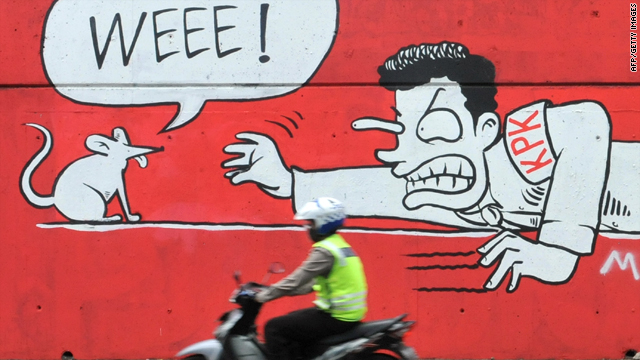 A policeman rides past a mural in Jakarta on November 24, 2009, that symbolizes how hard the country's Corruption Eradication Commission (KPK) efforts to combat corruptions are.