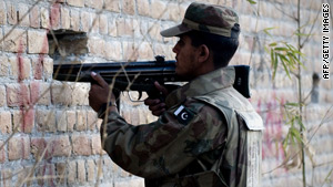 A Pakistani soldier aims his weapon through holes in a wall outside a besieged mosque in Rawalpindi.