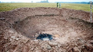 Officials check out a crater Monday near Mazsalaca, Latvia.