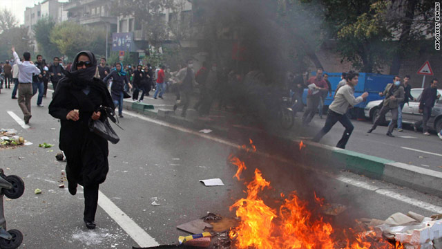 Demonstrators run from riot police Wednesday in Tehran, Iran. More than 100 were arrested.
