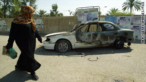 A woman walks past a burned-out car after the 2007 incident in which Blackwater security personnel killed 17 people.