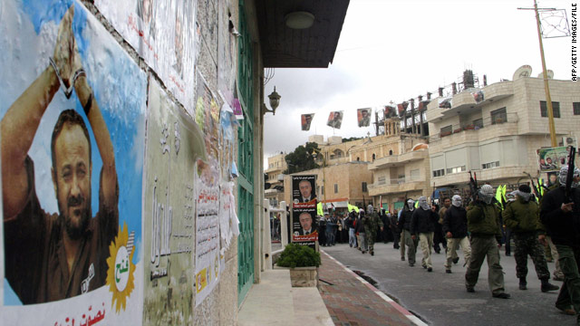 Palestinian militants march past a wall poster of Marwan Barghouti in 2006.