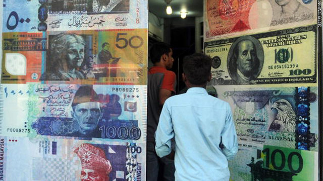 Pakistani customers enter a foreign currency exchange shop in Karachi, Pakistan, on October 14, 2010.