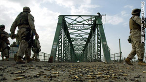 U.S. soldiers in 2004 walk on the bridge where the burned bodies of American contractors were hung.