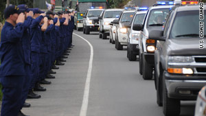 Coast Guardsmen salute a procession of police cars carrying the urns of two slain police officers Wednesday.