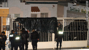 Police guard the house in Juarez, Mexico, where 14 people were shot to death on Friday night.