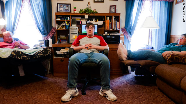 Austin Mobley, 16, sits between his parents, Allen and Tracy Mobley, in their Elkland, Missouri, house. His mom has dementia.