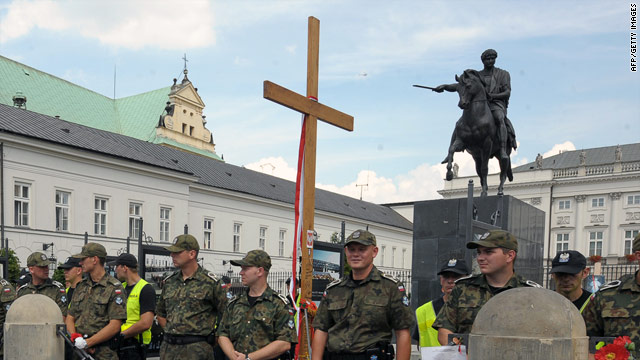 Police stand before a wooden cross dedicated to the late President Lech Kaczynski during a protest this month in Warsaw.