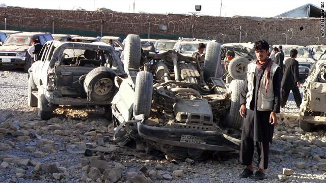 Afghans inspect the debris of a suicide bombing, including an overturned car, on the outskirts of Kandahar in April.