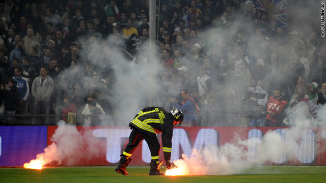 A fireman collects one of the flares thrown onto the pitch that forced the Italy v Serbia match to be abandoned.