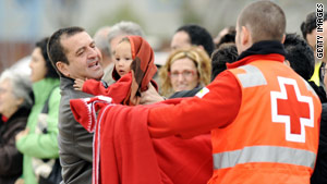 A Red Cross member at a Madrid airport January 12 hands blankets to arriving Spanish and Haitian earthquake survivors.