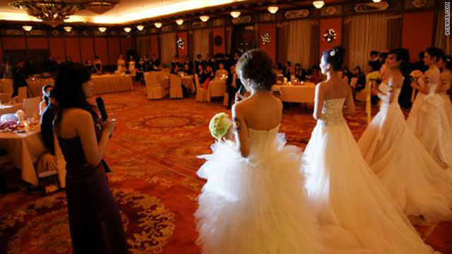 Brides to be? Young women selected for their eligibility pose in wedding gowns at an event for millionaire bachelors.