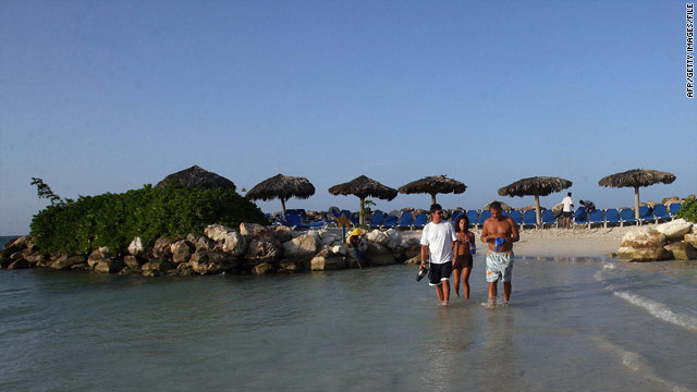 Tourists walk on a beach at a resort in northwest Jamaica. The country is heavily dependent on tourism.