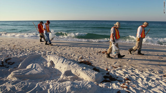 Workers pick up oil residue Tuesday that has washed up on Pensacola Beach, Florida.