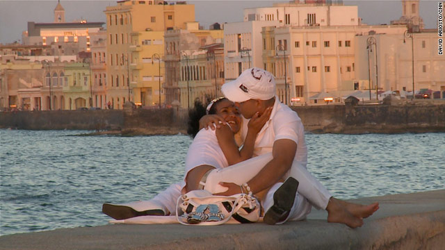 A young couple embraces at sunset along the Malecon in Havana, Cuba.