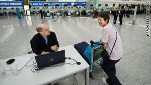 Alain de Botton chats with a passenger at his desk in Terminal 5 of Heathrow Airport.