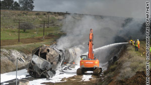 Firefighters work to put out the flames at the site of the train derailment Sunday in Keene, California.