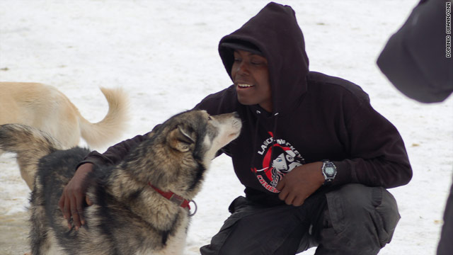 Rookie musher Newton Marshall of Jamaica bonds with borrowed lead dog Larry in Anchorage, Alaska.