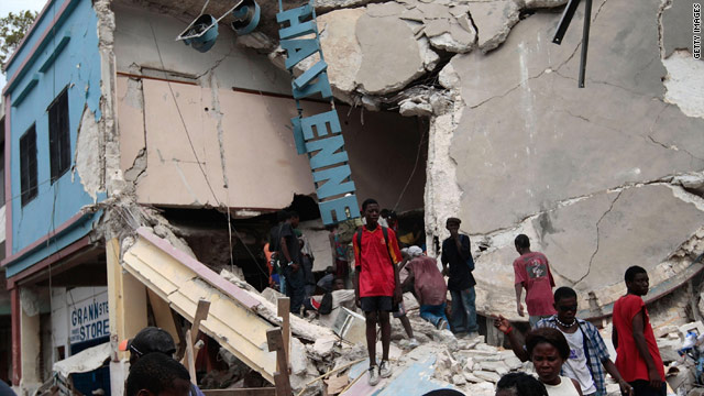 People walk in front of a destroyed shop in Port-au-Prince's downtown commercial district on Tuesday.