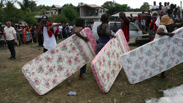 Quake victims receive mattresses from CARE International at a displaced people's settlement outside Leogane.