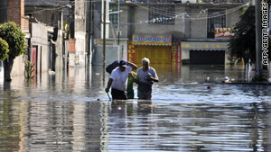 People wade through the flooded Valle de Chalco, on the outskirts of the Mexico City area, on Friday.