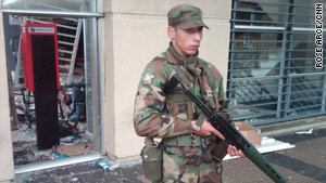 A soldier guards a looted mall on a main street in Concepcion, Chile, on Monday.