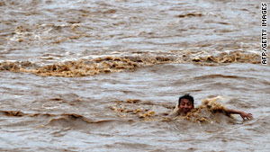 A boy tries to cross the overflowed Huiza River in La Libertad, south of San Salvador.