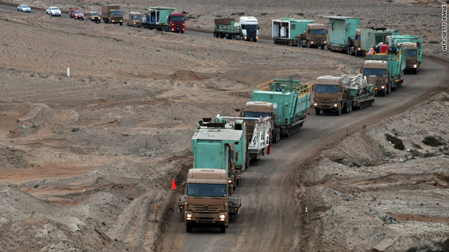 Trucks carrying parts for a new drilling rig arrive Friday at a mine where 33 miners are trapped.