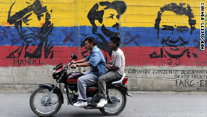 Motorcyclists ride past a mural showing dead FARC leaders in  El Palo, Colombia.