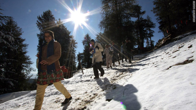 Tourists walk on fresh snow Monday near Shimla in Himachal Pradesh, northern India.