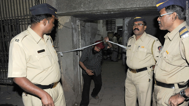 Police look on while a resident exits the building housing deceased laywer Shahid Azmi's office in Mumbai on Thursday.