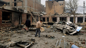 Afghan bystanders walk among debris at the site of Friday's deadly attack in Kabul.