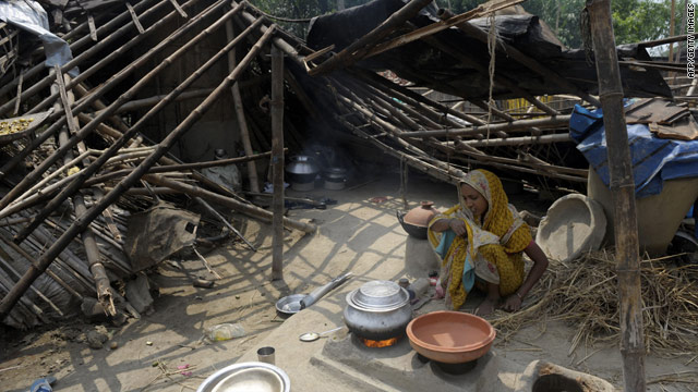 An Indian woman cooks beside her collapsed hut in the West Bengal village of Karandighi on Thursday following a storm.