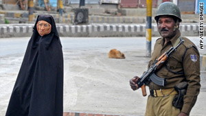 A pedestrain walks past a soldier on Friday in Srinagar.