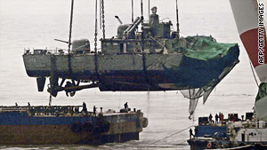 The South Korean naval ship Cheonan is lifted by a crane onto a barge in mid April, 2010.