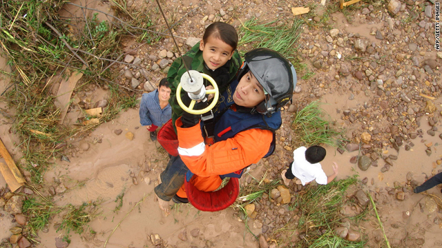 A member of the Chinese airforce holds on to a child during the airlifting of a group of villagers who were trapped after their village was hit by flooding in Jinxiu, southwest China's Guangxi region.