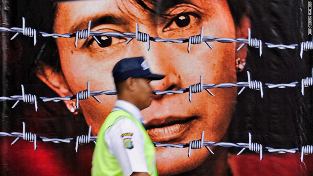 A guard passes a picture of imprisoned Aung San Suu Kyi on the front gate of the British embassy in Jakarta, Indonesia.