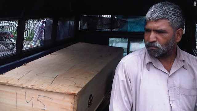 A volunteer sits next to a coffin at a makeshift morgue at Islamabad, Pakistan's main hospital.