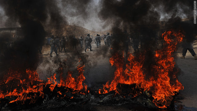 Afghan police run past a fire as they chase anti-US demonstrators during riots in Kabul on September 15, 2010.
