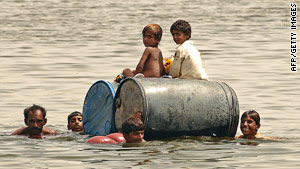 Children cross a flooded area on empty oil drums in Pakistan's Sindh Province on Thursday.