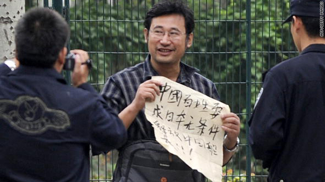 A protestor shows his banner declaring "Chinese people demand Japan to release unconditionally the Chinese captain" as police film him in front of the Japanese embassy in Beijing on September 20, 2010.