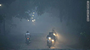 The air is thick with volcanic ash as residents flee on motorcycle in Klaten district, central Java.