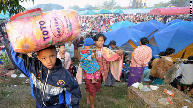 A boy carries a bag as Myanmar refugees arrived in a temporary camp set up at a police base on the border town of Mae Sot on Tuesday.